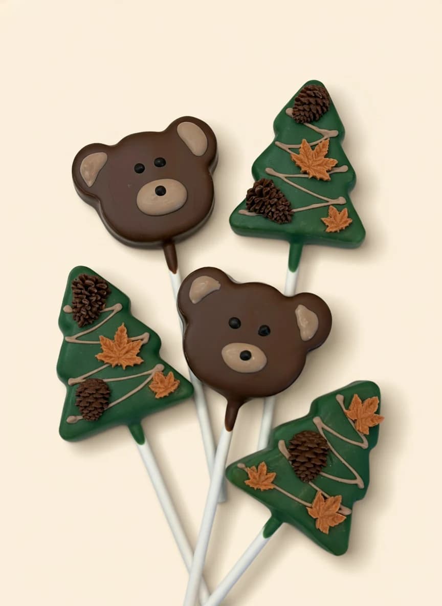 Bear face and pine tree shaped cake pops in chocolate.