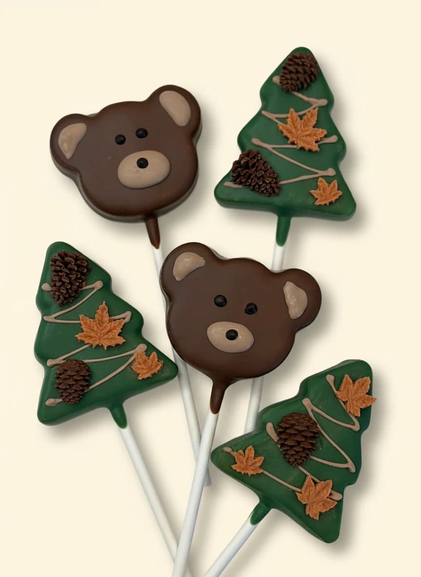 Bear face and pine tree shaped cake pops with chocolate decoration.